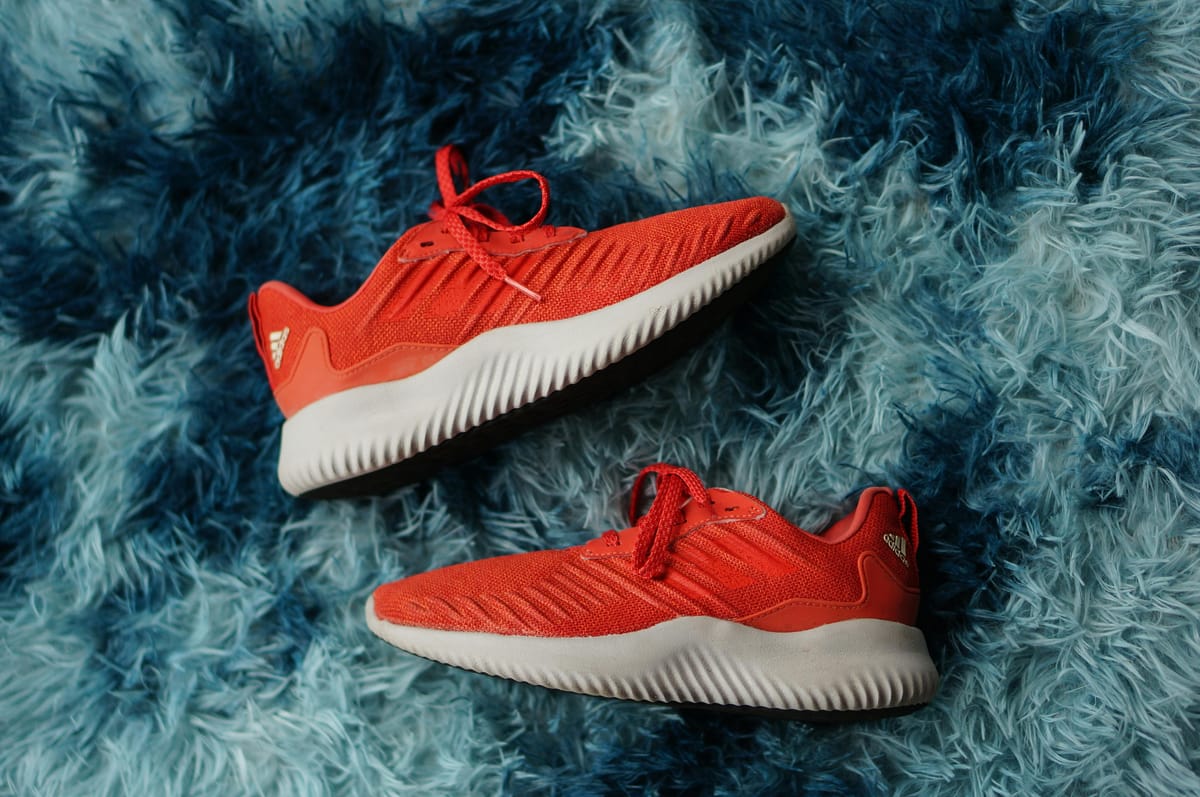 A pair of running shoes by a doorway in natural light.