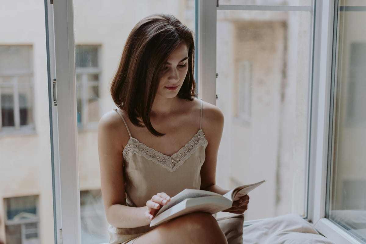 A person reading by a window in natural light.