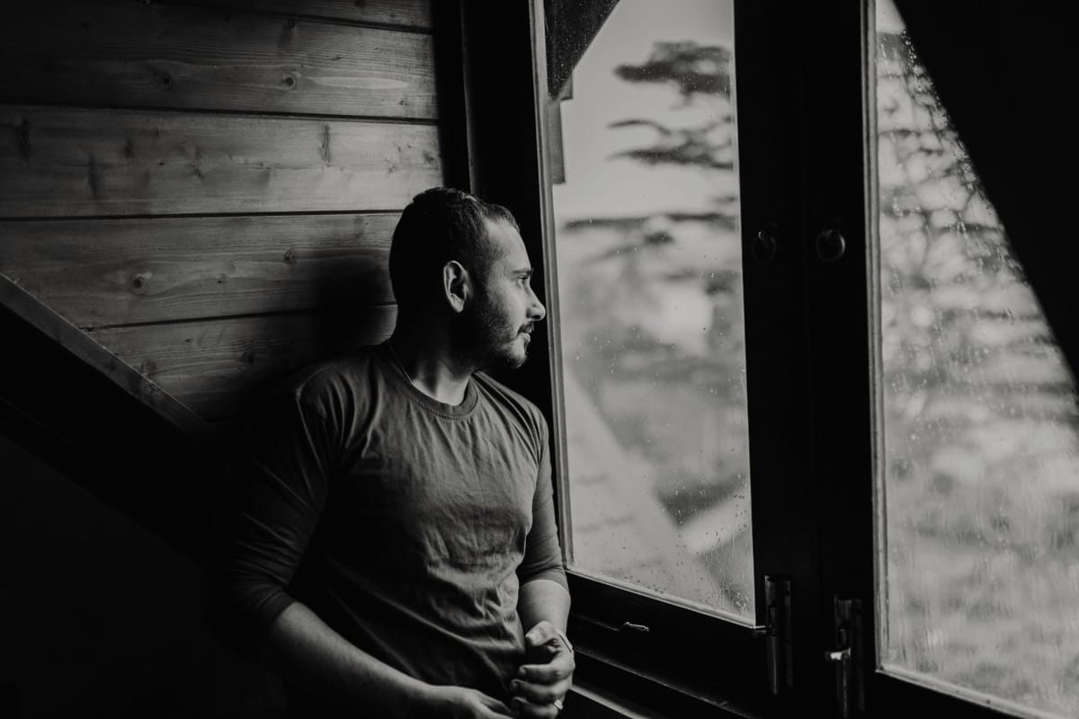A view of a thoughtful person at a window in soft natural light.