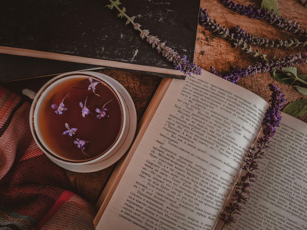 An open book on a wooden table with a cup of tea.