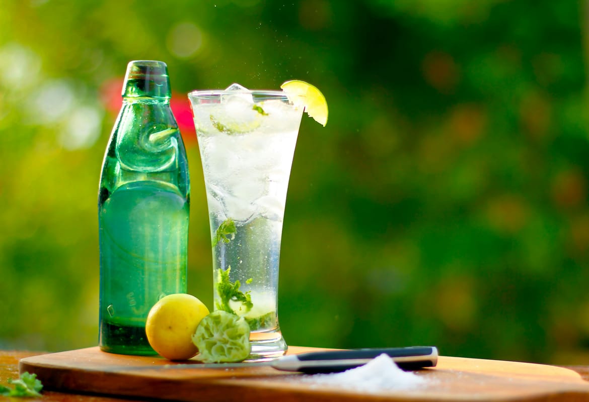 A glass of sparkling water with lime on a wooden bar.